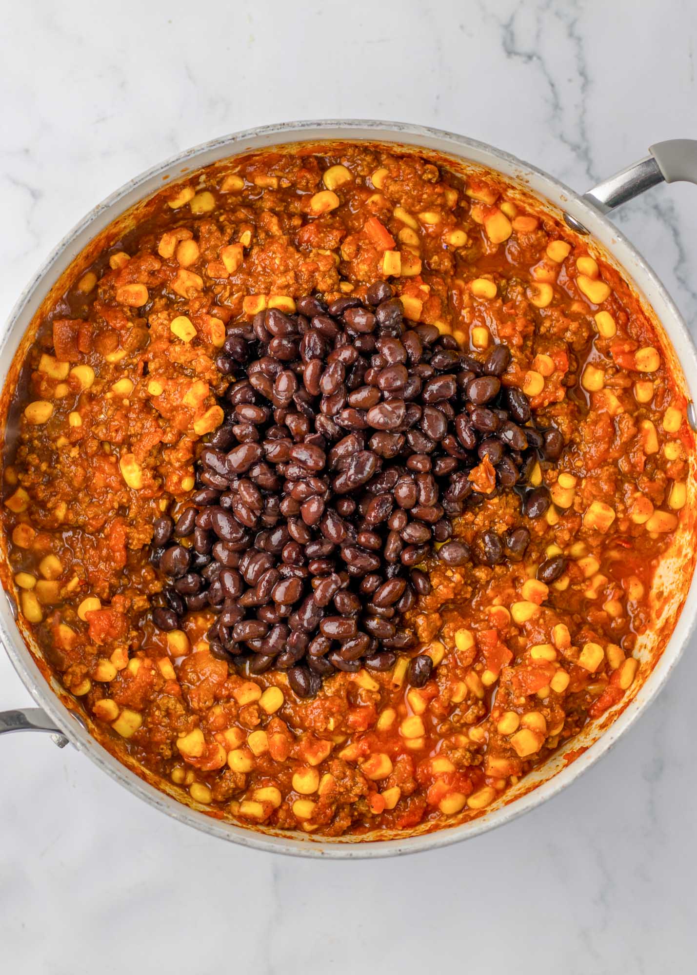 Added beans to the chili in a skillet