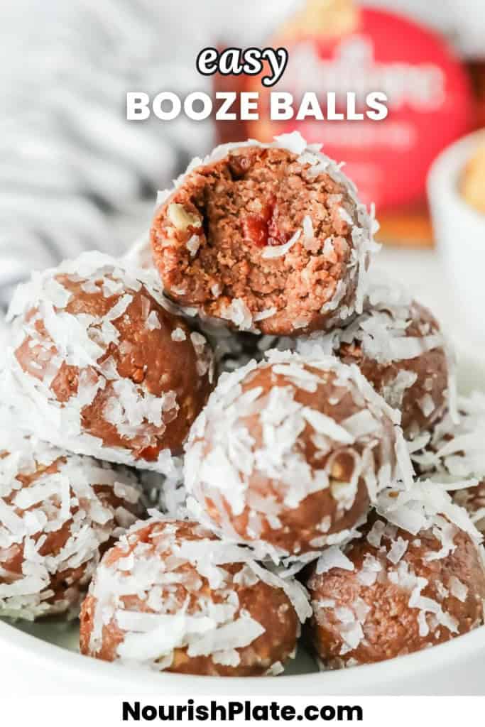 Close-up of chocolate Amaretto balls coated in shredded coconut, stacked in a bowl with one ball bitten open to reveal a nutty chocolate interior and a cherry piece inside.
