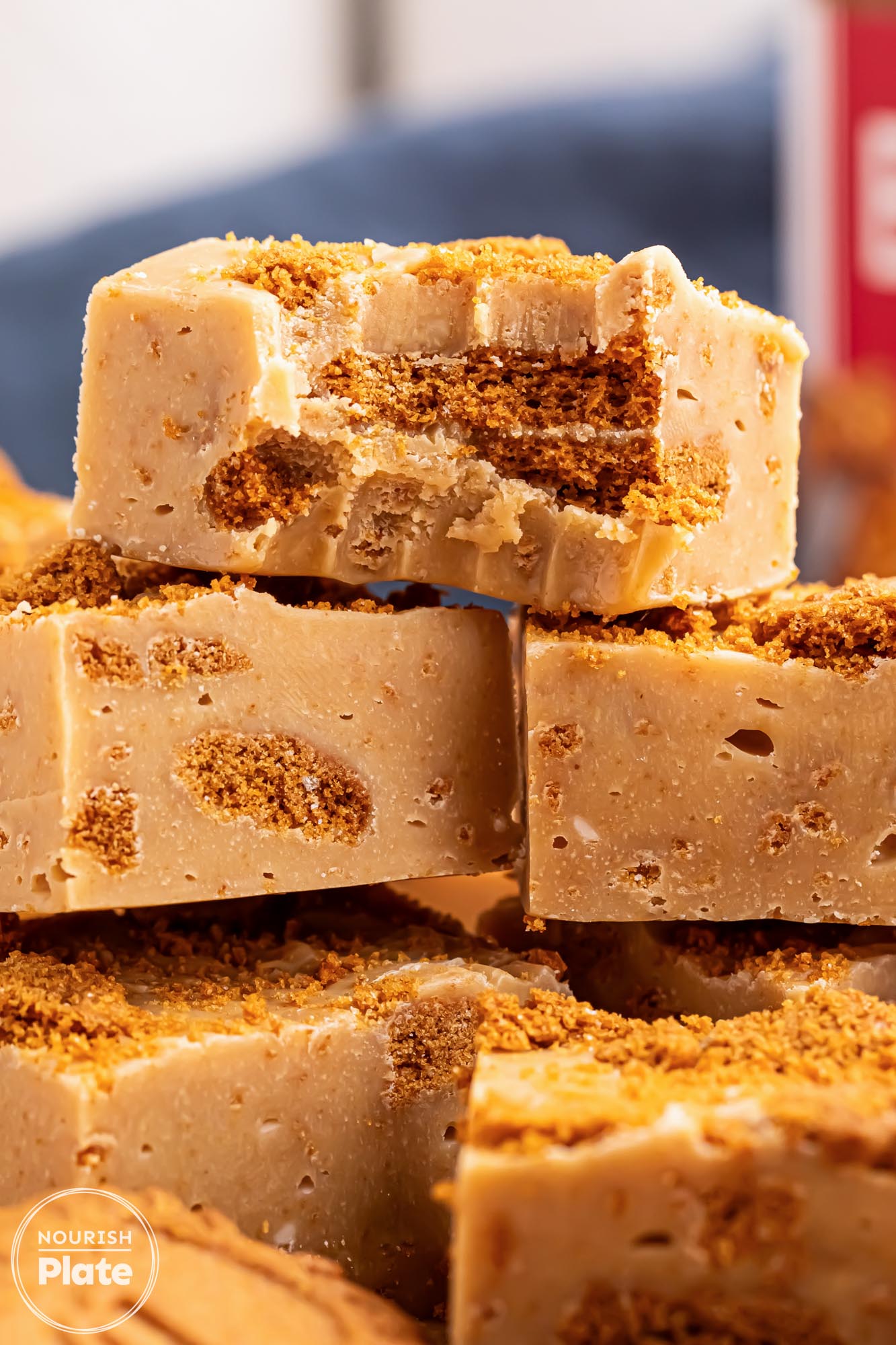 Close-up of stacked cookie butter fudge squares showing a creamy texture with chunks of Biscoff cookies and golden crumbs on top.