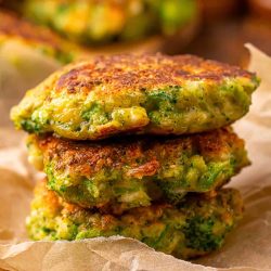 Close up of pan fried broccoli fritters with feta cheese, stacked and showing a golden crust and tender texture inside.
