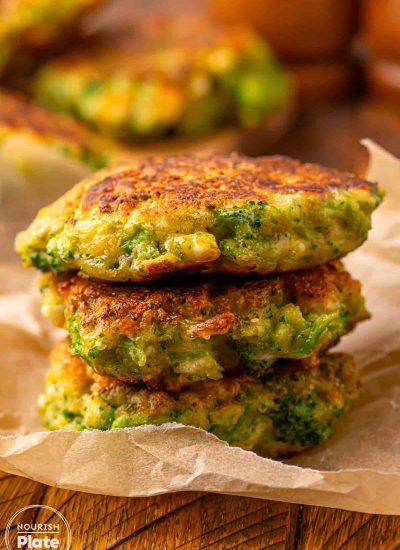Close up of pan fried broccoli fritters with feta cheese, stacked and showing a golden crust and tender texture inside.