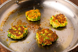 Close up of pan fried broccoli fritters with feta cheese, showing a golden crust and tender texture inside.