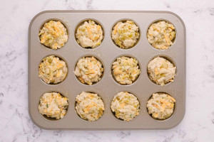 Beer cheese muffin batter divided evenly into a greased 12 cup muffin pan before baking.