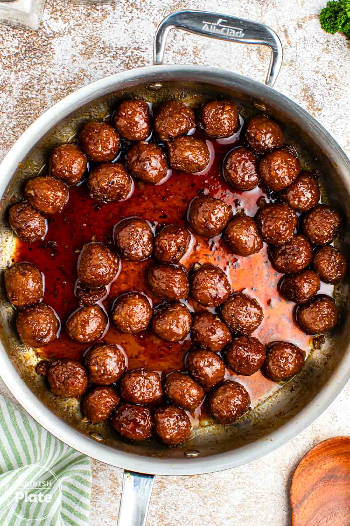 Overhead shot of glazed asian meatballs in a stainless steel pan
