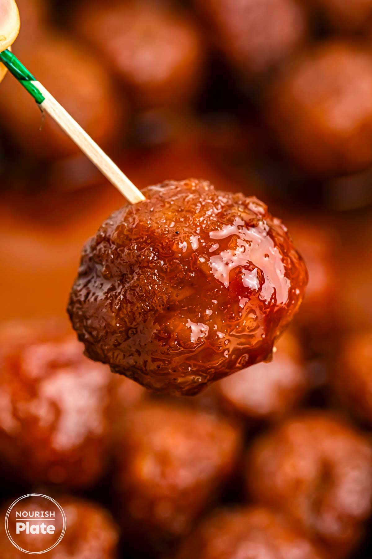 Close up shot of an asian glazed meatball on a pick