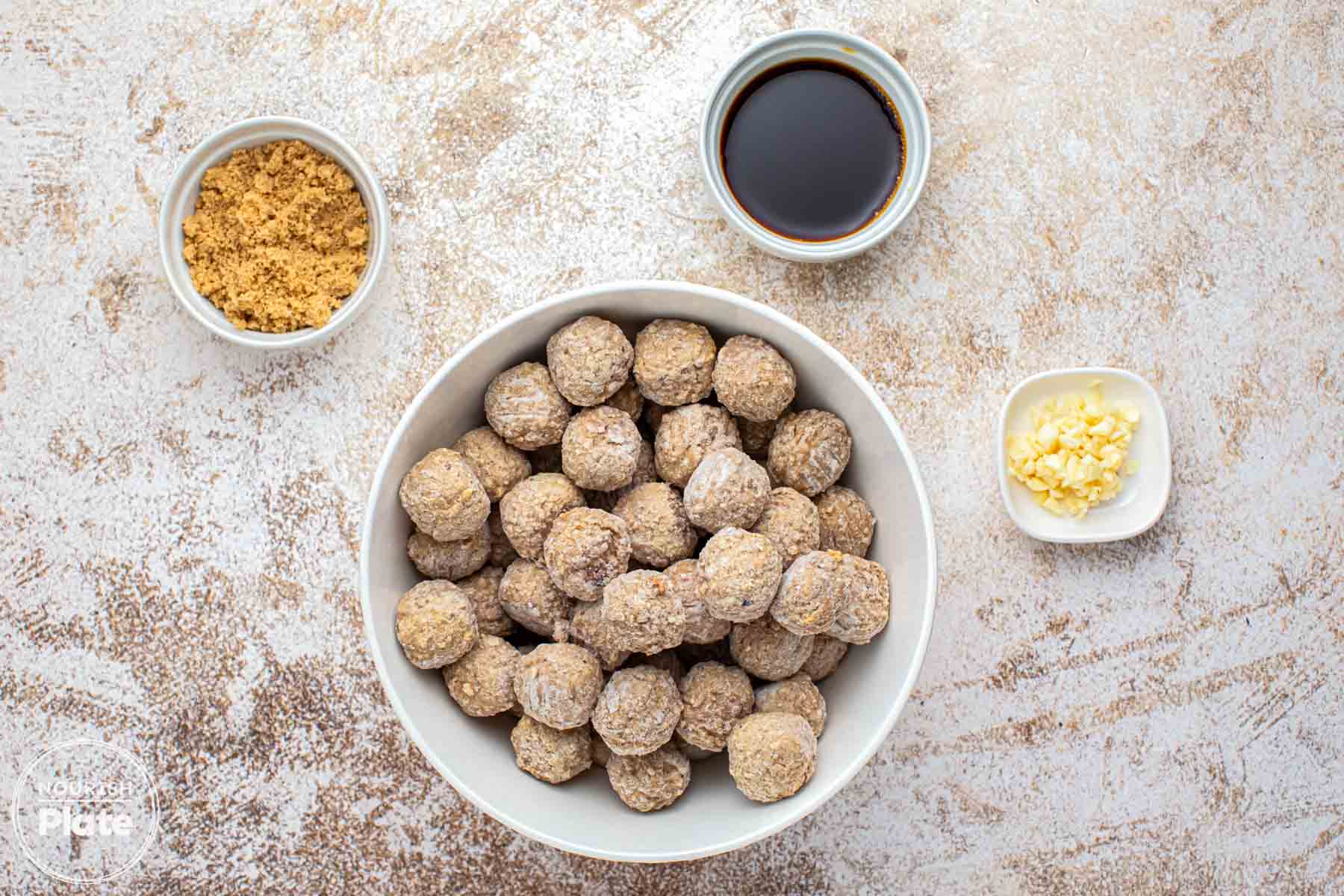 Ingredients needed to make glazed asian meatballs including frozen meatballs, soy sauce, brown sugar and garlic.