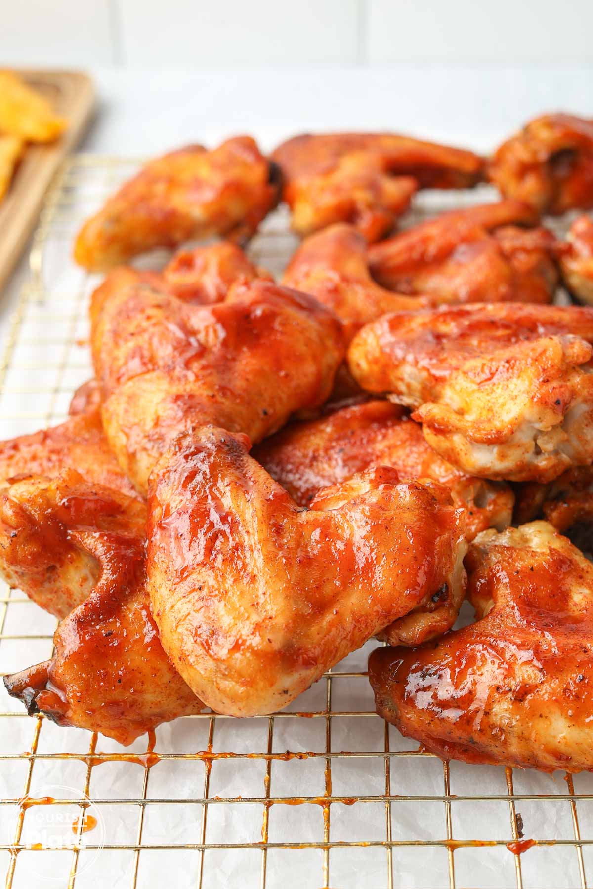 Baked BBQ chicken wings coated in glossy BBQ sauce on a wire rack.