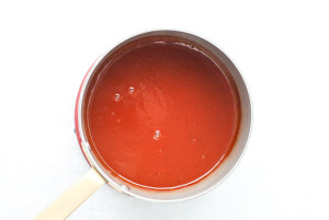 Red barbecue sauce simmering in a saucepan.