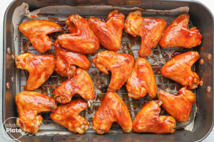 Baked chicken wings glazed with barbecue sauce on a wire rack.