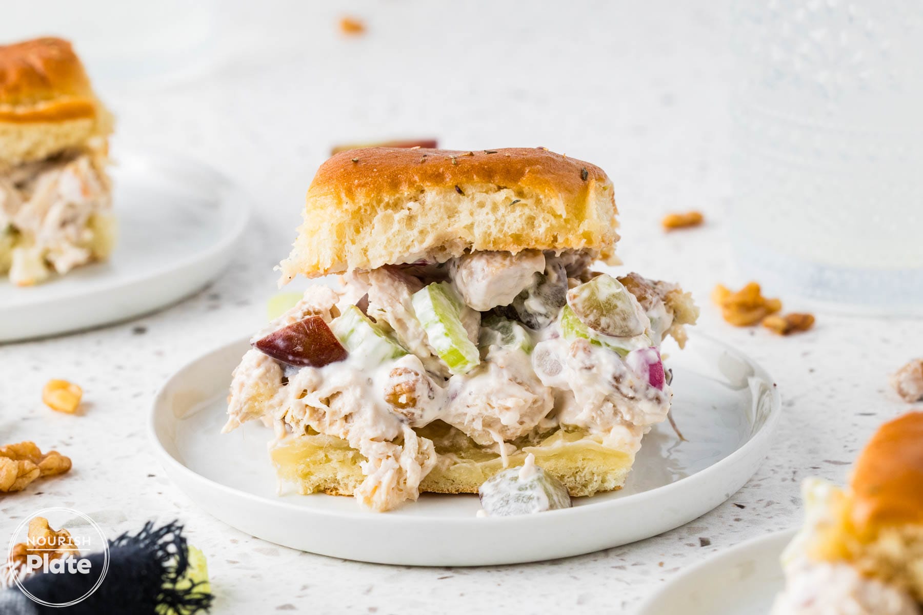 Chicken salad slider with grapes, celery, walnuts, and creamy filling served on a white plate.