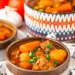 Bowl of Instant Pot beef stew with tender beef, carrots, potatoes, peas, and rich tomato gravy.