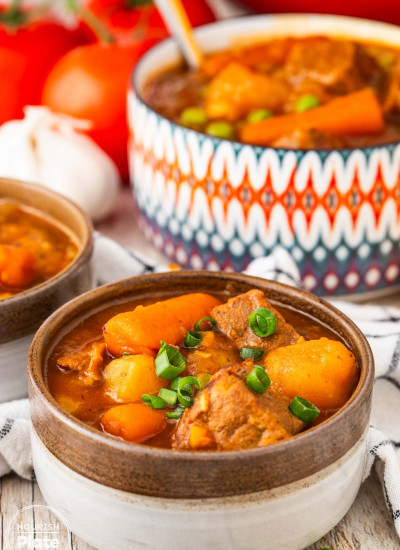 Bowl of Instant Pot beef stew with tender beef, carrots, potatoes, peas, and rich tomato gravy.