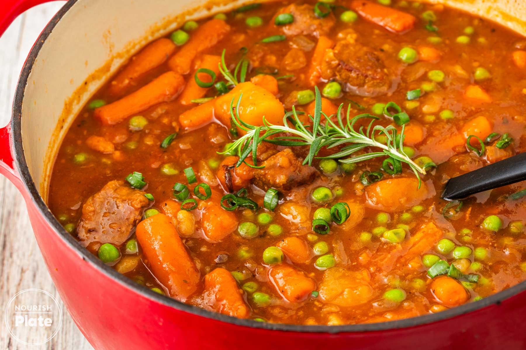 Instant Pot beef stew with tender beef, carrots, potatoes, peas, and rosemary in a rich tomato gravy.