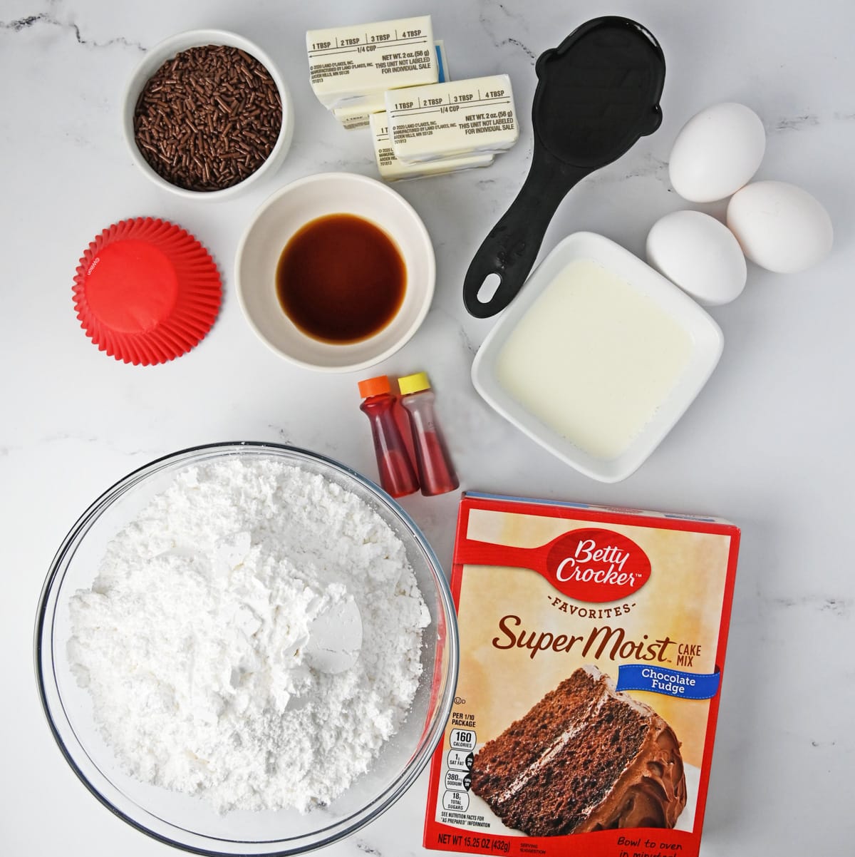 Ingredients for sunflower cupcakes including chocolate cake mix, butter, powdered sugar, heavy cream, eggs, gel food coloring, and chocolate sprinkles